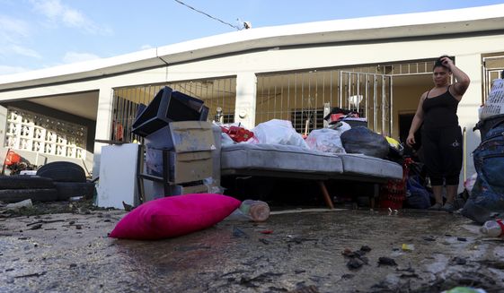 A woman looks at her water-damaged belongings after flooding caused by Hurricane Fiona tore through her home in Toa Baja, Puerto Rico, Tuesday, Sept. 20, 2022. On Monday, Oct. 3, 2022, President Joe Biden will survey damage from Hurricane Fiona in Puerto Rico, where tens of thousands of people are still without power two weeks after the storm hit. (AP Photo/Stephanie Rojas, File)