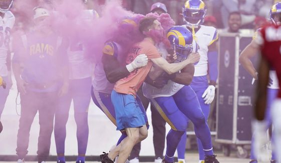 A protester is hit by Los Angeles Rams defensive end Takkarist McKinley, middle left, and linebacker Bobby Wagner during the first half of an NFL football game between the San Francisco 49ers and the Rams in Santa Clara, Calif., Monday, Oct. 3, 2022. (AP Photo/Godofredo A. Vásquez)