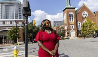 Khadidah Stone stands on the dividing line between her old Alabama congressional District 7, to her right with River City Church, and her new district, District 2, to her left, in downtown Montgomery, Ala., Tuesday, Sept. 20, 2022. The line splits Montgomery between two congressional districts and is the subject of a high-stakes case that will go before the U.S. Supreme Court on Tuesday. (AP Photo/Vasha Hunt)