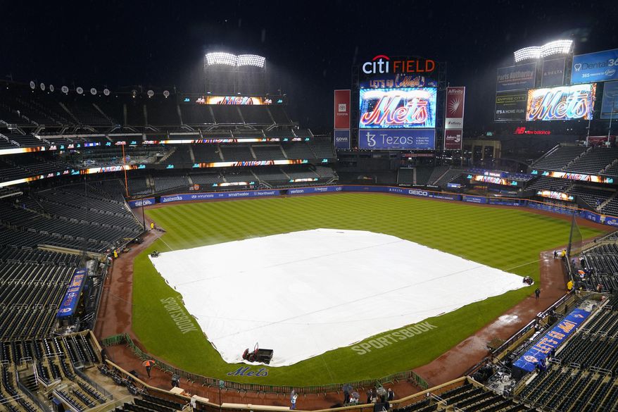 Security stands on the field as rain falls before a baseball game between the New York Mets and the Washington Nationals, Monday, Oct. 3, 2022, in New York. (AP Photo/Frank Franklin II)
