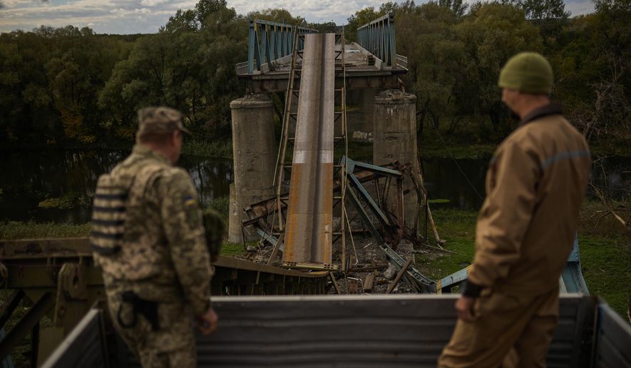 Ukrainian soldiers remove metal structure pieces as they work on a bridge damaged during fighting with Russian troops in Izium, Ukraine, Monday, Oct. 3, 2022. A series of embarrassing military losses for Moscow in recent weeks has presented a growing challenge for prominent hosts of Russian news and political talk shows scrambling to find ways to paint Kyiv&#39;s gains in a way that is still favorable to the Kremlin. (AP Photo/Francisco Seco)