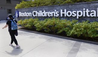 A woman walks past a sign outside the Boston Children&#x27;s Hospital, Thursday, Aug. 18, 2022, in Boston. The American Academy of Pediatrics, the American Medical Association and the Children&#x27;s Hospital Association are asking U.S. Attorney General Merrick Garland to investigate and prosecute people who are threatening violence against children&#x27;s hospitals and physicians that provide gender-affirming health care. (AP Photo/Charles Krupa, File)