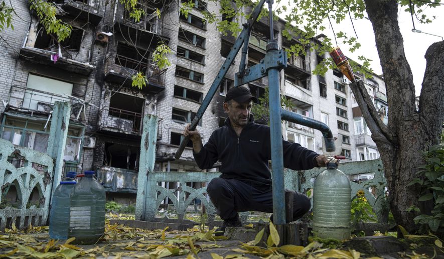 A man pumps water in front of destroyed house in the recently recaptured town of Lyman, Ukraine, Monday, Oct. 3, 2022. Lyman resident live without electricity, gas and running water since mid of May. (AP Photo/Evgeniy Maloletka)