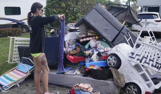 Alice Pujols goes through someone else&#39;s discarded items for clothes and shoes for her family Monday, Oct. 3, 2022, in Fort Myers, Fla. Pujols&#39;s home was completely destroyed after her home flooded due to rising waters caused by Hurricane Ian. (AP Photo/Marta Lavandier)