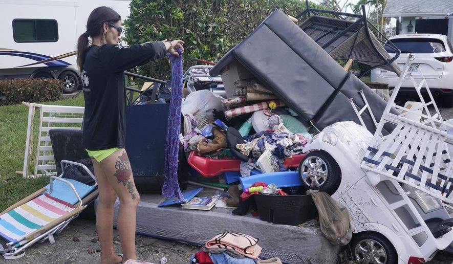 Alice Pujols goes through someone else&#x27;s discarded items for clothes and shoes for her family Monday, Oct. 3, 2022, in Fort Myers, Fla. Pujols&#x27;s home was completely destroyed after her home flooded due to rising waters caused by Hurricane Ian. (AP Photo/Marta Lavandier)