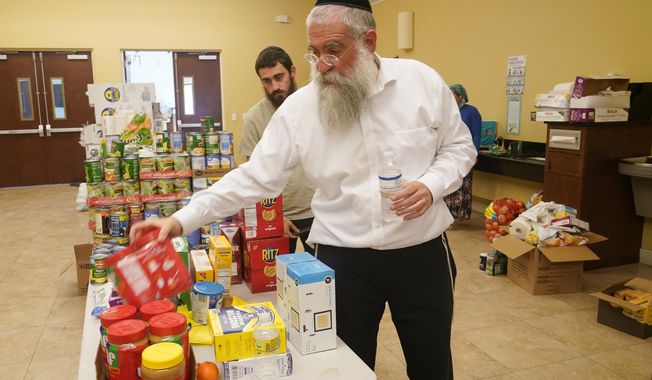 Rabbi Yitzchok Minkowicz supervises the pantry inside the Chabad Lubavitch of Southwest Florida, Monday, Oct. 3, 2022, in Fort Myers, Fla. The synagogue has been transformed into a full-fledged community center with food trucks and a pantry. They plan on celebrating Yom Kippur on Tuesday. (AP Photo/Marta Lavandier)