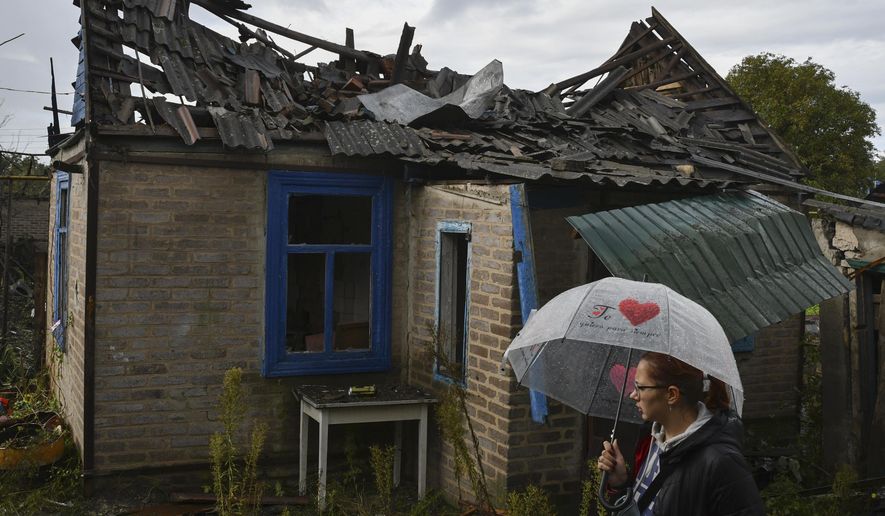 Local resident Ekaterina, 22, stands next to her residential building that was damaged after an overnight Russian attack in Kramatorsk, Ukraine, Tuesday, Oct. 4, 2022. (AP Photo/Andriy Andriyenko)