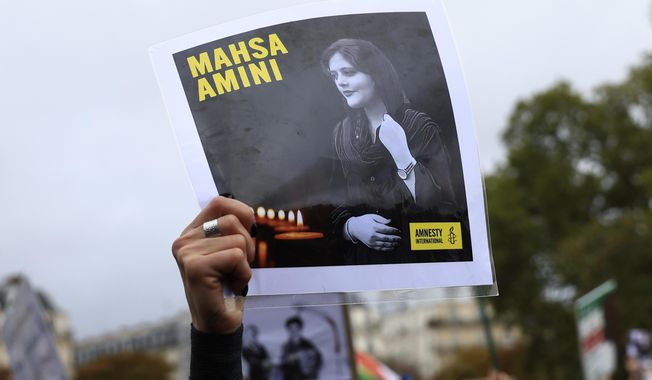 FILE - A protester shows a portrait of Mahsa Amini during a demonstration to support Iranian protesters standing up to their leadership over the death of a young woman in police custody, Sunday, Oct. 2, 2022 in Paris.  Anti-government demonstrations erupted Saturday, Oct. 8,  in several locations across Iran as the most sustained protests in years against a deeply entrenched theocracy entered their fourth week. The protests erupted Sept. 17, after the burial of 22-year-old Amini, a Kurdish woman who had died in the custody of Iran&#x27;s feared morality police.   (AP Photo/Aurelien Morissard)