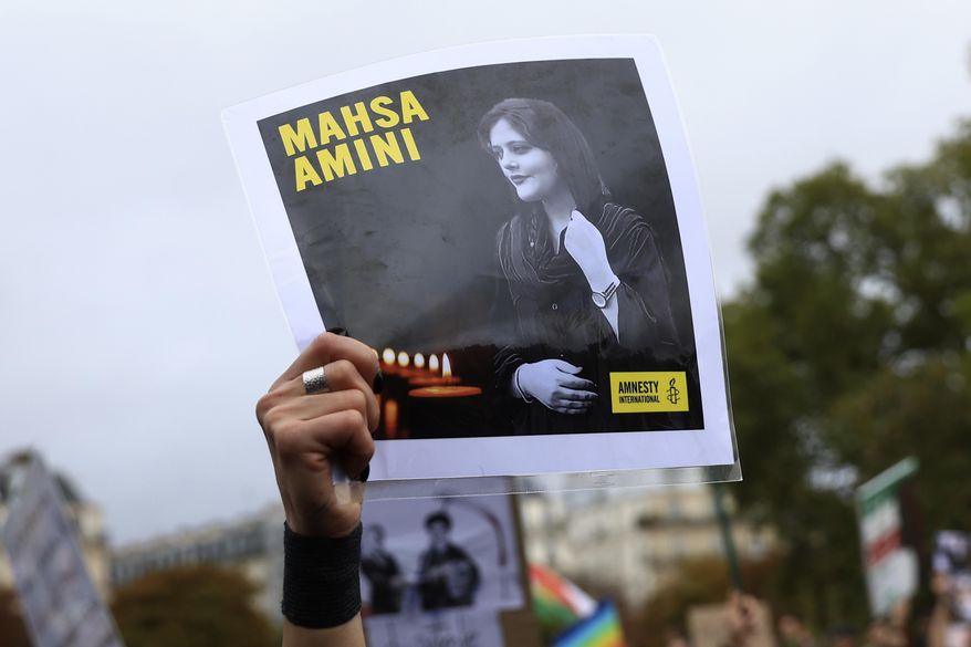 FILE - A protester shows a portrait of Mahsa Amini during a demonstration to support Iranian protesters standing up to their leadership over the death of a young woman in police custody, Sunday, Oct. 2, 2022 in Paris.  Anti-government demonstrations erupted Saturday, Oct. 8,  in several locations across Iran as the most sustained protests in years against a deeply entrenched theocracy entered their fourth week. The protests erupted Sept. 17, after the burial of 22-year-old Amini, a Kurdish woman who had died in the custody of Iran&#x27;s feared morality police.   (AP Photo/Aurelien Morissard)