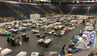 Cots cover the floor of Hertz Arena, an ice hockey venue that has been transformed into a massive relief shelter, in Estero, Fla., on Saturday, Oct. 8, 2022. More than 500 people were still housed at the arena more than a week after Hurricane Ian struck the southwest Florida coast. (AP Photo/Jay Reeves)