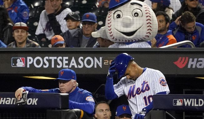 New York Mets manager Buck Showalter, left, watches play from the dugout as Eduardo Escobar (10) prepares to bat against the San Diego Padres during the eighth inning of Game 3 of a National League wild-card baseball playoff series, Sunday, Oct. 9, 2022, in New York. (AP Photo/John Minchillo)