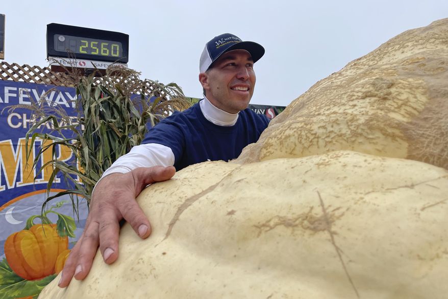 Travis Gienger from Anoka, Minn., embraces his winning pumpkin at the 49th World Championship Pumpkin Weigh-Off in Half Moon Bay, Calif., Monday, Oct. 10, 2022. (AP Photo/Haven Daley)