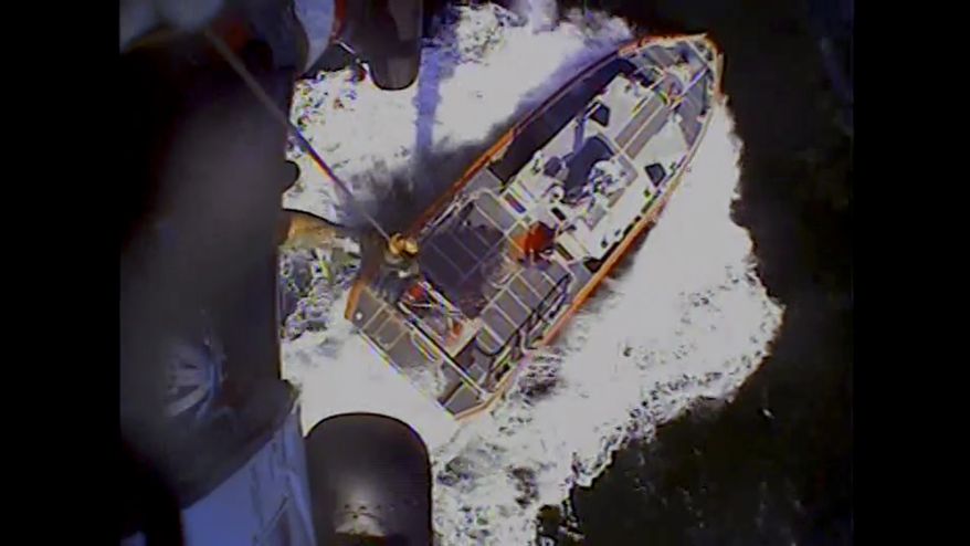 In this screenshot from video, the U.S. Coast Guard rescues boaters off the coast of Empire, La., on Sunday, Oct. 9, 2022. Three men whose fishing boat sank in the Gulf of Mexico off the Louisiana coast were rescued after surviving for more than a day despite being attacked by sharks that inflicted deep cuts on their hands and shredded one of their life jackets, according to their rescuers. (U.S. Coast Guard via AP)