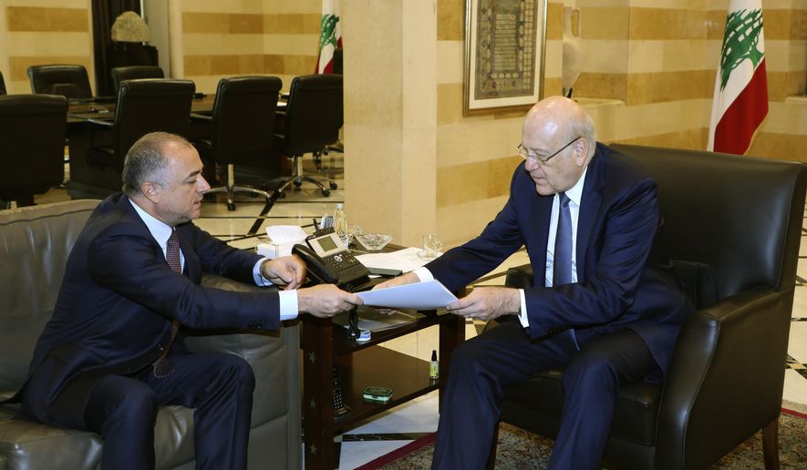 In this photo released by Lebanon&#39;s official government photographer Dalati Nohra, Lebanese Prime Minister Najib Makati, right, receives the final draft of the maritime border agreement between Lebanon and Israel from his deputy Elias Bou Saab who leads the Lebanese negotiating team, in Beirut, Lebanon, Tuesday, Oct. 11, 2022. Israel&#39;s prime minister said Tuesday that the country has reached a &quot;historic agreement&quot; with neighboring Lebanon over their shared maritime border after months of U.S.-brokered negotiations. (Dalati Nohra via AP)