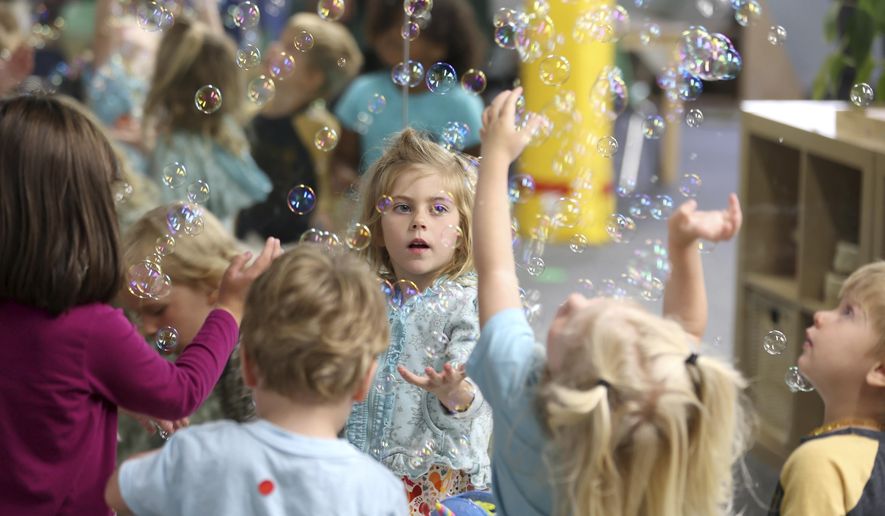 Lova Robinson, 4, plays with bubbles at the Bumble Art Studio day care in Astoria, Ore., Friday, Sept. 2, 2022. From Oregon to New York, demand for child care far exceeds supply. Families are growing increasingly desperate as providers deal with staffing shortages exacerbated by the coronavirus pandemic as well as historically low pay worsened by inflation. (AP Photo/Craig Mitchelldyer)