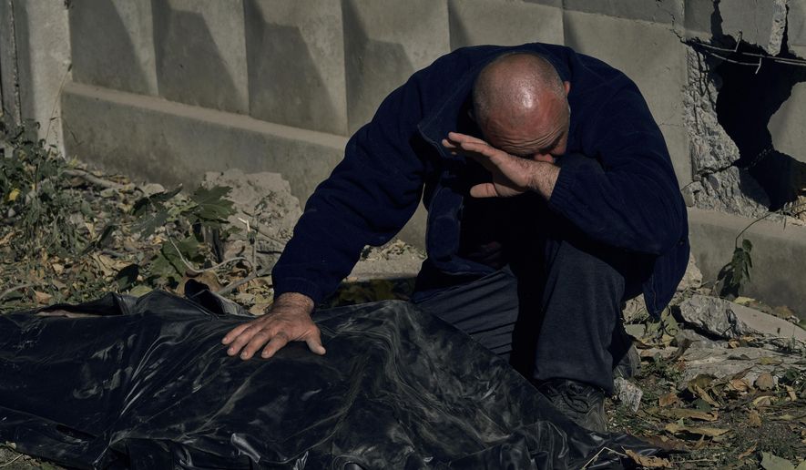 A man reacts near the body of his cousin, killed in a Russian rocket attack in Mykolaiv, Ukraine, Thursday, Oct. 13, 2022. (AP Photo/LIBKOS)