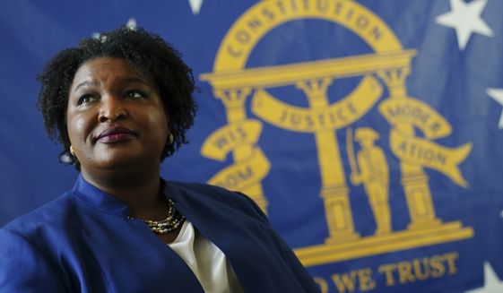 FILE - Democratic candidate for Georgia Governor Stacey Abrams poses for a portrait in front of the State Seal of Georgia on Aug. 8, 2022, in Decatur, Ga. The Georgia governor&#x27;s race is a rematch of 2018, when Brian Kemp narrowly defeated Stacey Abrams. (AP Photo/John Bazemore, File)