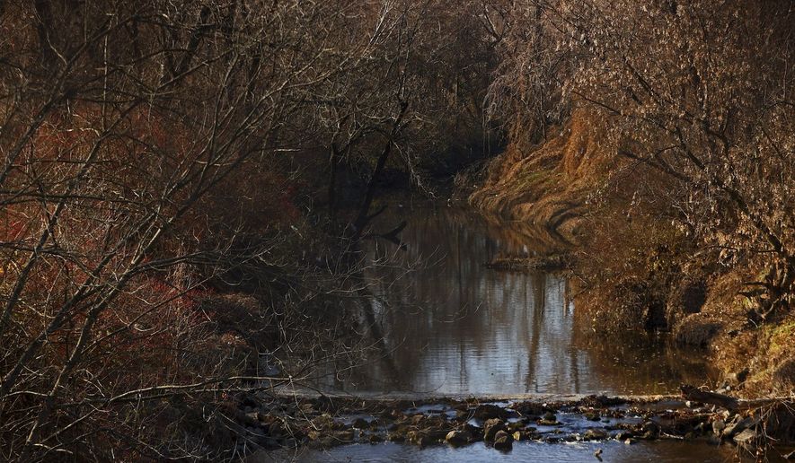 Water flows in Coldwater Creek on Thursday, Dec. 9, 2021, behind a row of homes at Belcroft Drive and Old Halls Ferry Road in Missouri's St. Louis County. Environmental investigation consultants have found significant radioactive contamination at an elementary school, which sits in the flood plain of Coldwater Creek which was contaminated by nuclear waste from weapons production during World War II. (Christian Gooden/St. Louis Post-Dispatch via AP)