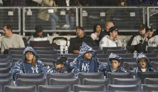 Baseball fans wait out a rain delay for Game 5 of an American League Division baseball series between the New York Yankees and the Cleveland Guardians, Monday, Oct. 17, 2022, in New York. (AP Photo/Seth Wenig)