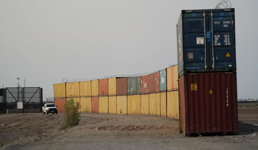 Border Patrol agents patrol along a line of shipping containers stacked near the border on Aug. 23, 2022, near Yuma, Ariz. The Cocopah Indian Tribe is welcoming the federal government&#39;s call for the state of Arizona to remove a series of double-stacked shipping containers placed along the U.S.-Mexico border near the desert city of Yuma, saying they are unauthorized and violate U.S. law. (AP Photo/Gregory Bull, File)