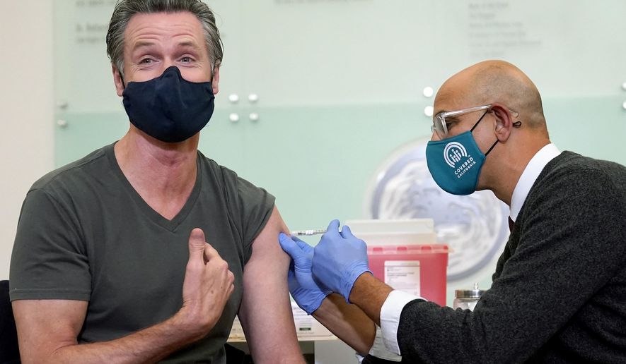California Gov. Gavin Newsom, left, receives a Moderna COVID-19 vaccine booster shot from California Health and Human Services Secretary Dr. Mark Ghaly at Asian Health Services in Oakland, Calif., on Oct. 27, 2021. On Monday, Oct. 17, 2022, Newsom announced he will lift the coronavirus state of emergency at the end of February 2023. The announcement will officially end all of the pandemic-related executive orders Newsom has issued since 2020. (AP Photo/Jeff Chiu, File)