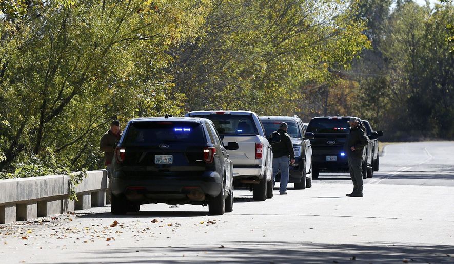 Officials investigate a bridge near the Deep Fork River where bodies were found in Okmulgee, Okla, on Monday, Oct. 17, 2022. (Stephen Pingry/Tulsa World via AP)