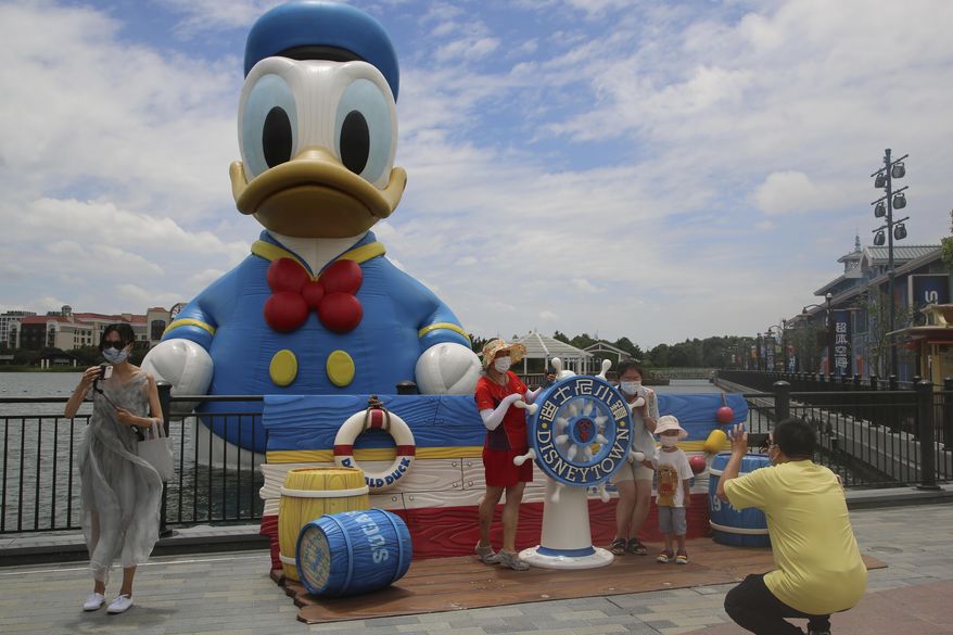 Visitors pose for photos outside the Disney Resort theme park, Thursday, June 30, 2022, in Shanghai. (AP Photo/Chen Si, File)