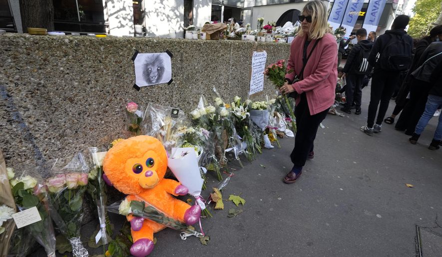 A woman lays flowers outside the building where the body of 12-year-old schoolgirl was discovered in a trunk, in Paris, Wednesday, Oct. 19, 2022. France has been &amp;quot;profoundly shaken&amp;quot; by the murder of a 12-year-old schoolgirl, whose body was found in a plastic box, dumped in a courtyard of a building in northeastern Paris, the government spokesman Olivier Veran said on Wednesday. (AP Photo/Michel Euler)
