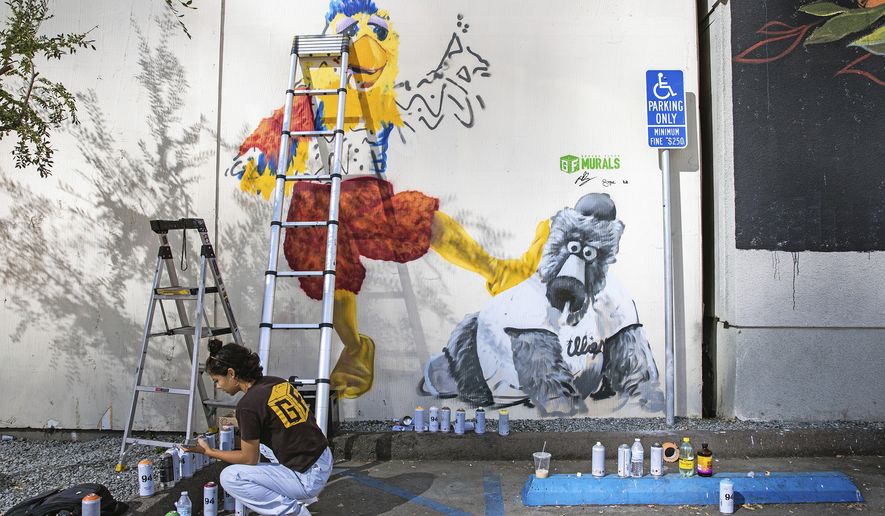 Ground Floor Murals artist Signe Ditona works on a mural of the San Diego Chicken mascot stomping on the Phillie Phanatic mascot in downtown San Diego, Monday, Oct. 17, 2022. The San Diego Padres and the Philadelphia Phillies are tied 1-1 in the baseball NL Championship Series. (Adriana Heldiz/The San Diego Union-Tribune via AP) **FILE**