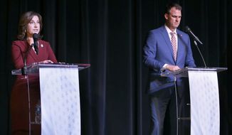 Oklahoma Republican Gov. Kevin Stitt, right, listens as his Democratic challenger Joy Hofmeister, the state’s public schools superintendent, speaks during a debate at Will Rogers Theatre in Oklahoma City, Wednesday, Oct. 19, 2022. (Sarah Phipps/The Oklahoman via AP)