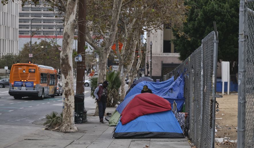 Homeless men stand by their tents along the street across from Los Angeles City Hall, on Saturday, Oct. 22, 2022. (AP Photo/Richard Vogel)