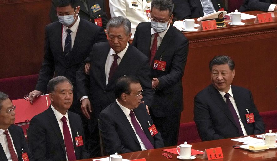 Chinese President Xi Jinping, right, looks on as former Chinese President Hu Jintao, standing at center, touches the shoulder of Premier Li Keqiang, center, as he is assisted to leave the hall during the closing ceremony of the 20th National Congress of China&#x27;s ruling Communist Party at the Great Hall of the People in Beijing, Saturday, Oct. 22, 2022. (AP Photo/Andy Wong)