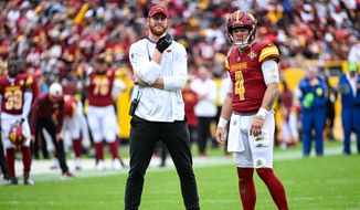 Washington Commanders quarterback Taylor Heinicke (4) and injured quarterback Carson Wentz watch the video board during a lengthy review on a possible fumble during the first half against the Green Bay Packers at FedEx Field, Landover, MD, October 23, 2022. (Photo by Brian Murphy)