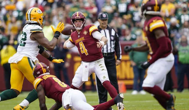 Washington Commanders quarterback Taylor Heinicke (4) looks to pass under pressure during the first half of an NFL football game against the Green Bay Packers, Sunday, Oct. 23, 2022, in Landover, Md. (AP Photo/Susan Walsh)