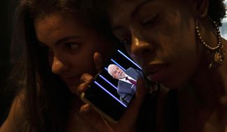 Women listen on a mobile phone to an interview of former president Luiz Inacio Lula da Silva, who is running again for president, with Jornal Nacional on TV Globo, outside a bar in Rio de Janeiro, Brazil, Thursday, August 25, 2022. The Superior Electoral Court, the country&#39;s top electoral authority, announced Thursday, Oct, 20, that it would be banning &amp;quot;false or seriously decontextualized&amp;quot; content that “affects the integrity of the electoral process.” No request from a prosecutor or complainant is necessary for the court to take action. (AP Photo/Bruna Prado, File)