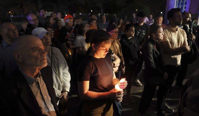 Marie Crane, center, holds a candle during a vigil in Tower Grove Park for the victims of a school shooting at Central Visual &amp; Performing Arts High School in St. Louis on Monday, Oct. 24, 2022. (David Carson/St. Louis Post-Dispatch via AP)