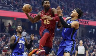 Cleveland Cavaliers guard Donovan Mitchell (45) passes between Orlando Magic forward Paolo Banchero (5) and guard Terrence Ross (31) during the first half of a NBA basketball game, Wednesday, Oct. 26, 2022, in Cleveland. (AP Photo/Ron Schwane)
