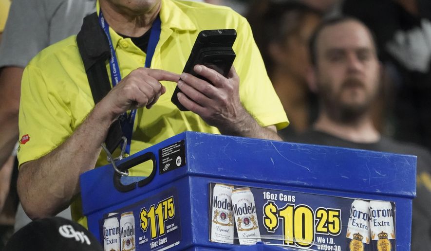 A beer vendor figures out the price for a baseball fan during a baseball game between the Cleveland Guardians and Chicago White Sox Tuesday, Sept. 20, 2022, in Chicago. Persistently high inflation and gas prices are looming over sports and the monetary pipeline that resumed when fans returned to games amid the pandemic. (AP Photo/Charles Rex Arbogast)