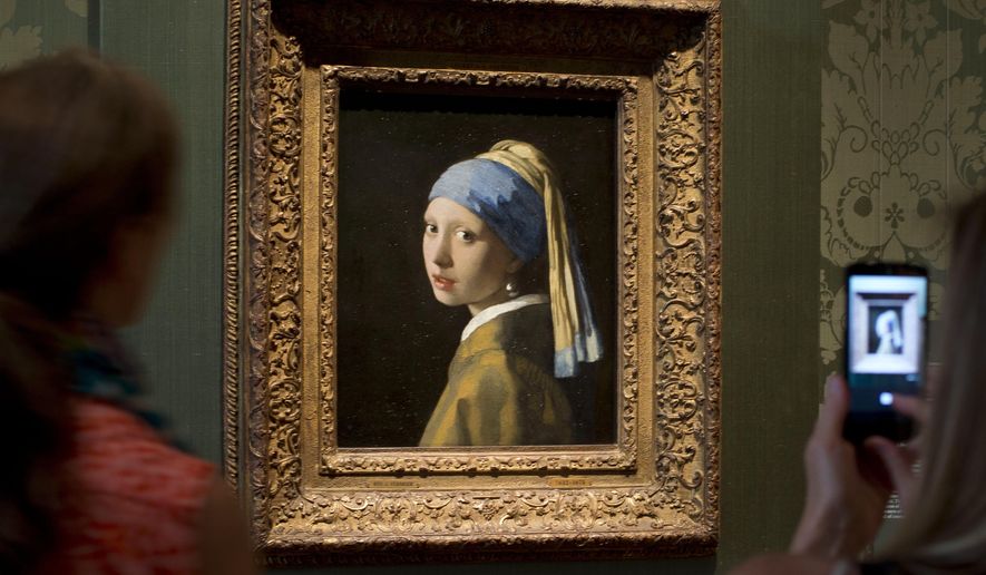 Visitors take pictures of Johannes Vermeer&#x27;s Girl with a Pearl Earring (approx. 1665) during a preview for the press of the renovated Mauritshuis in The Hague, Netherlands, June 20, 2014. The Vermeer masterpiece “Girl with a Pearl Earring” has become the latest artwork targetted by climate activists in a protest at the Mauritshuis museum in The Hague on Thursday, Oct. 27, 2022. The museum did not immediately return calls and emails for comment after a video of the protest was posted on Twitter. (AP Photo/Peter Dejong, file)