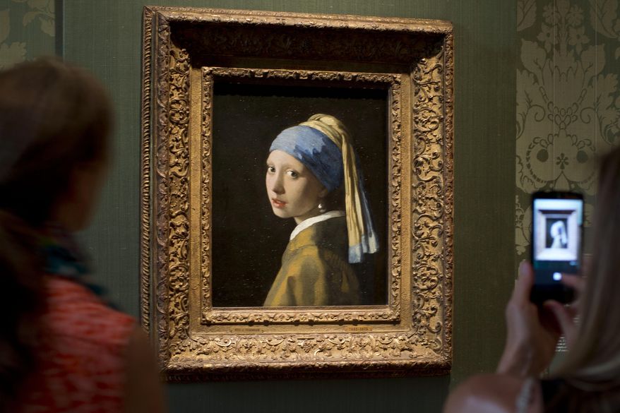 Visitors take pictures of Johannes Vermeer's Girl with a Pearl Earring (approx. 1665) during a preview for the press of the renovated Mauritshuis in The Hague, Netherlands, June 20, 2014. The Vermeer masterpiece “Girl with a Pearl Earring” has become the latest artwork targetted by climate activists in a protest at the Mauritshuis museum in The Hague on Thursday, Oct. 27, 2022. The museum did not immediately return calls and emails for comment after a video of the protest was posted on Twitter. (AP Photo/Peter Dejong, file)