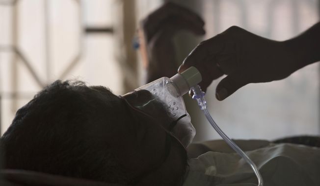 FILE - A relative adjusts the oxygen mask of a tuberculosis patient at a TB hospital on World Tuberculosis Day in Hyderabad, India, March 24, 2018. The number of people infected with tuberculosis, including the kind resistant to drugs, rose globally for the first time in years, according to a report issued Thursday, Oct. 27, 2022 by the World Health Organization. (AP Photo/Mahesh Kumar A., File)