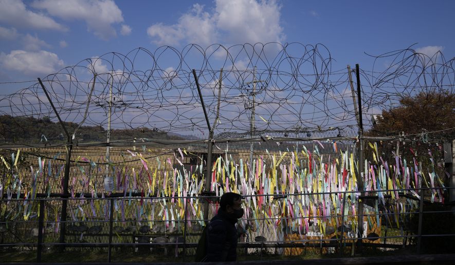 A visitor walks near the wire fences decorated with ribbons with messages wishing for the reunification of the two Koreas at the Imjingak Pavilion in Paju, South Korea, Friday, Oct. 28, 2022. (AP Photo/Lee Jin-man)