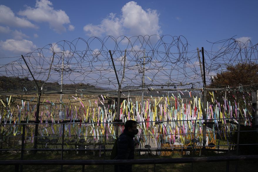 A visitor walks near the wire fences decorated with ribbons with messages wishing for the reunification of the two Koreas at the Imjingak Pavilion in Paju, South Korea, Friday, Oct. 28, 2022. (AP Photo/Lee Jin-man)
