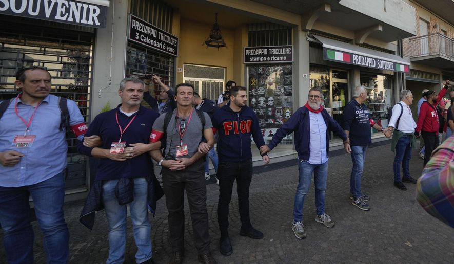 Demonstrators by the Italian Partisans association form a human chain to protect shops selling memorabilia of Fascist Dictator Benito Mussolini, during a march organized in Mussolini&#x27;s birthplace Predappio Friday, Oct. 28, 2022, to mark the 78th anniversary of the liberation of the town from the nazi-fascist occupation by Italian Partisans and Polish allied troops, which coincides with the 100th anniversary of the march on Rome. (AP Photo/Luca Bruno)