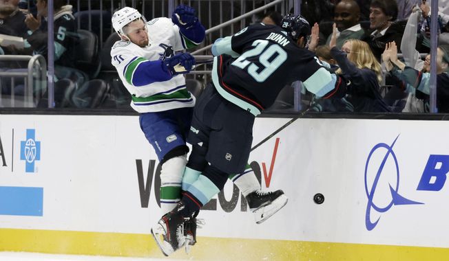 Vancouver Canucks left wing Nils Hoglander (21) collides with Seattle Kraken defenseman Vince Dunn (29) as they battle for the puck during the first period of an NHL hockey game, Thursday, Oct. 27, 2022, in Seattle. (AP Photo/John Froschauer)