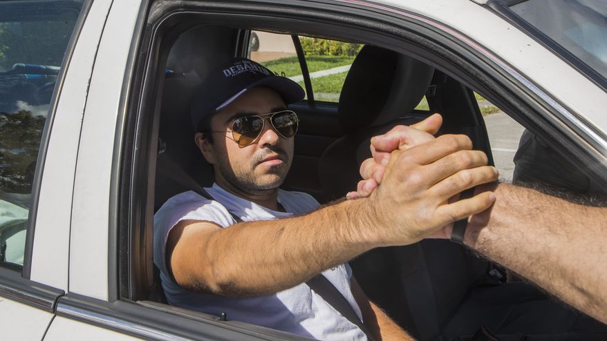 Christopher Monzon, the Republican Party canvasser attacked in Hialeah, Fla., while handing out fliers for U.S. Sen. Marco Rubio, is greeted by supporters during a rally in Hialeah on Saturday, Oct. 29, 2022, appearing in public for the first time since getting out of the hospital. (Pedro Portal/Miami Herald via AP)