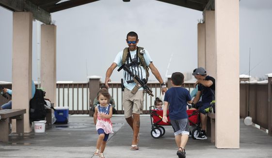 Michael Taylor, also known as &amp;quot;The Armed Fisherman&amp;quot;, walks along Pier 60 in Clearwater Beach, Fla., with his 2-year-old daughter Ocean and his assault rifle and fishing gear, on July 3, 2021. Advocates say permitless carry makes people safer. Opponents say it makes it more dangerous for ordinary people, and for police officers. (Octavio Jones/Tampa Bay Times via AP, File)