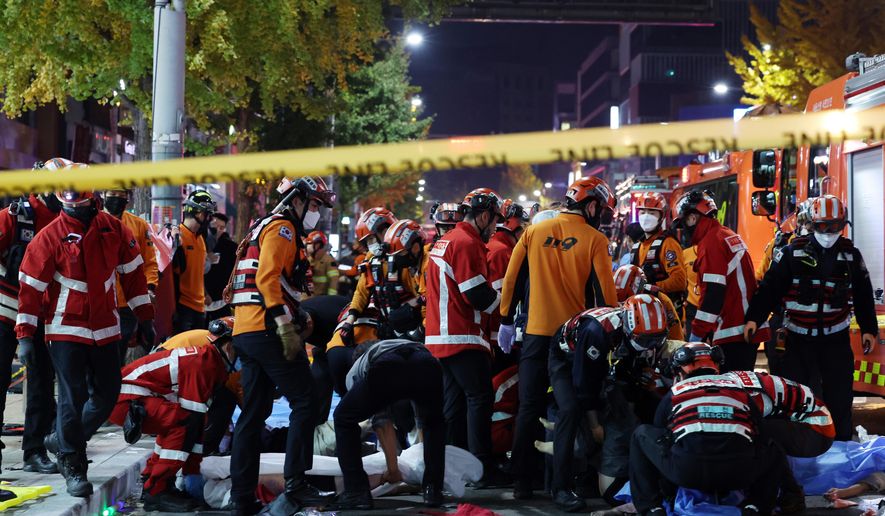 Rescue workers and firefighters work on the scene of a crushing accident in Seoul, South Korea, Saturday, Oct. 29, 2022. South Korean officials say dozens of people were in cardiac arrest after being crushed by a large crowd pushing forward on a narrow street during Halloween festivities in the capital Seoul. (Lee Ji-eun/Yonhap via AP)