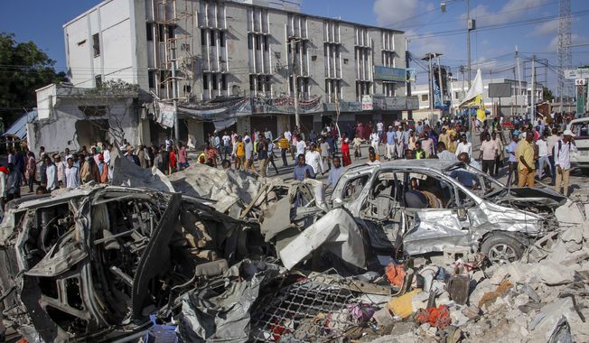 People walk amidst destruction at the scene, a day after a double car bomb attack at a busy junction in Mogadishu, Somalia Sunday, Oct. 30, 2022. Somalia&#x27;s president says multiple people were killed in Saturday&#x27;s attacks and the toll could rise in the country&#x27;s deadliest attack since a truck bombing at the same spot five years ago killed more than 500. (AP Photo/Farah Abdi Warsameh)