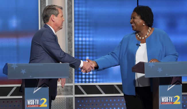 Republican Georgia Gov. Brian Kemp, left, shakes hands with Democratic challenger Stacey Abrams following a televised debate, in Atlanta, Sunday, Oct. 30, 2022. (AP Photo/Ben Gray)